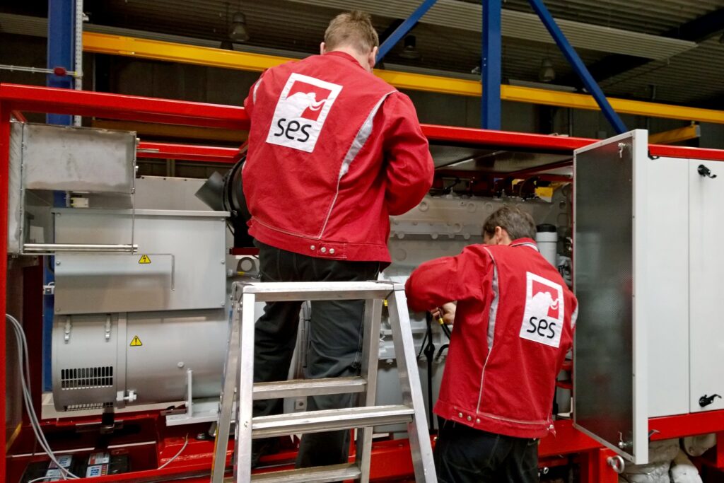 Zwei SES Mitarbeiter bauen ein Blockheizkraftwerk