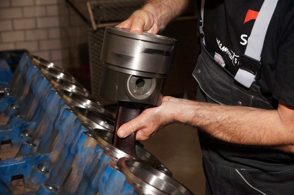 Das Bild zeigt einen SES Mitarbeiter, der einen BHKW-Motor repariert.